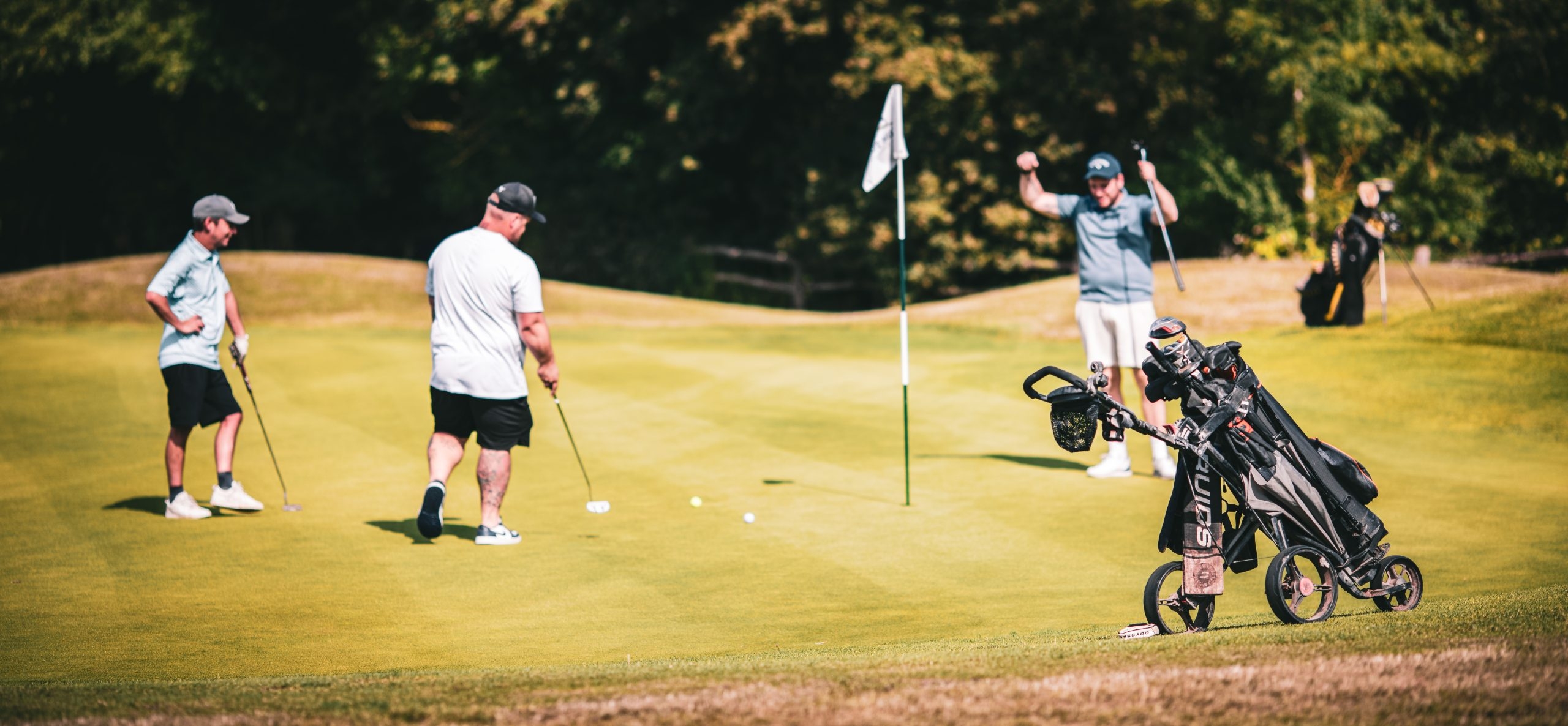 Golfer celebrating successful putt with companions watching on at Toot Hill golf course